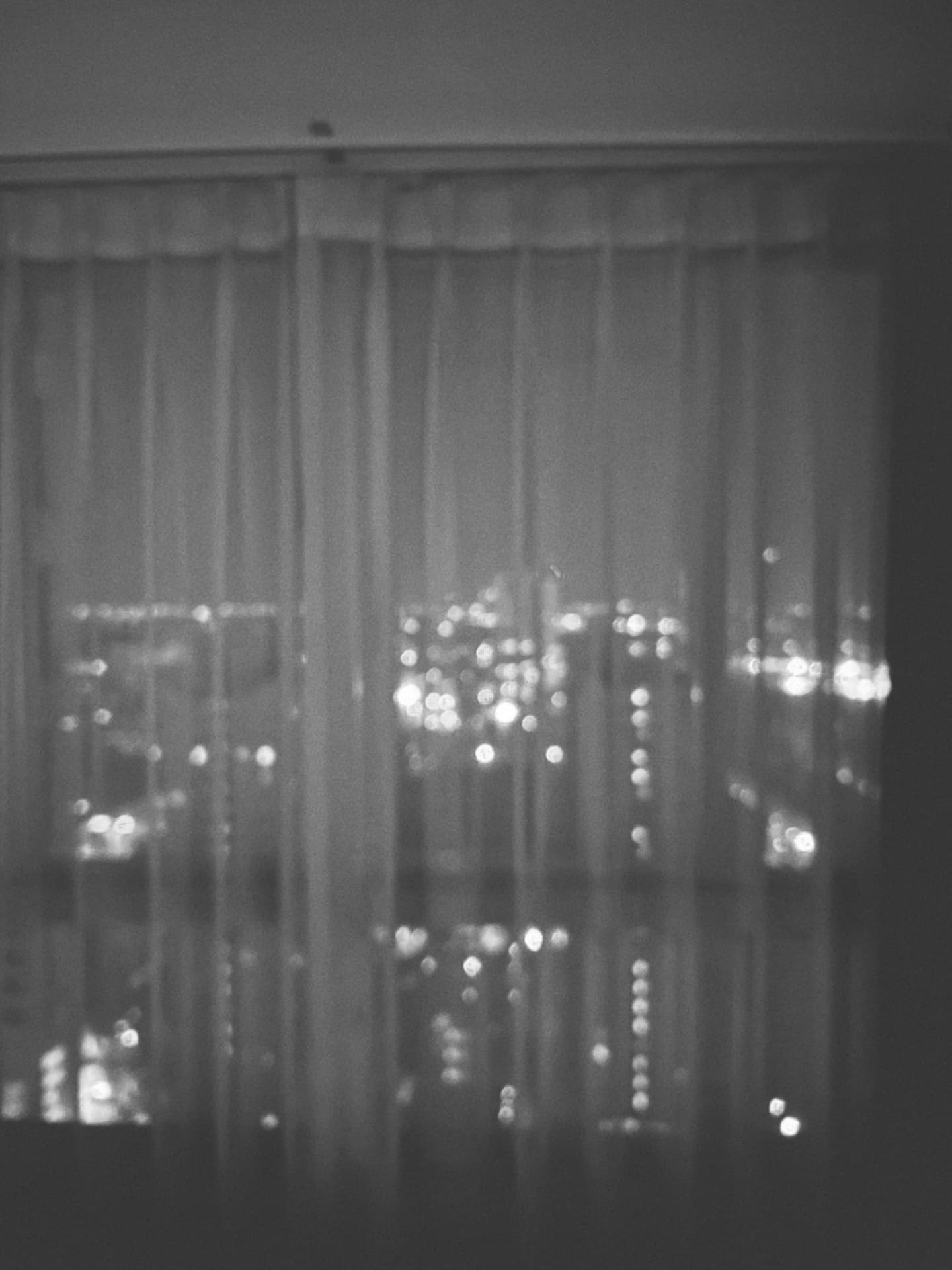 Tall towers rising over the rooftops at night, seen through a window
