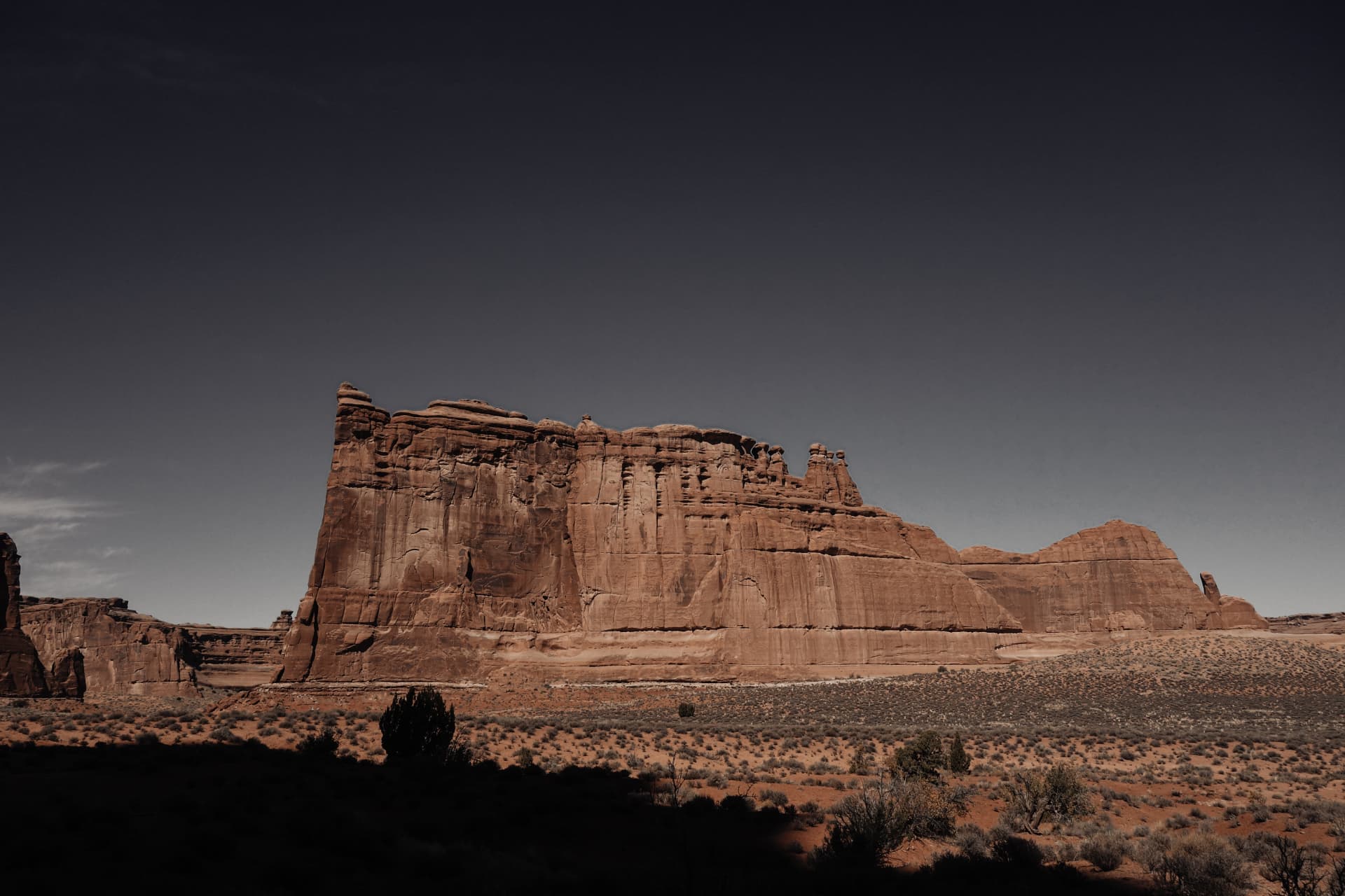 A red sandstone cliff wall under a darkening sky