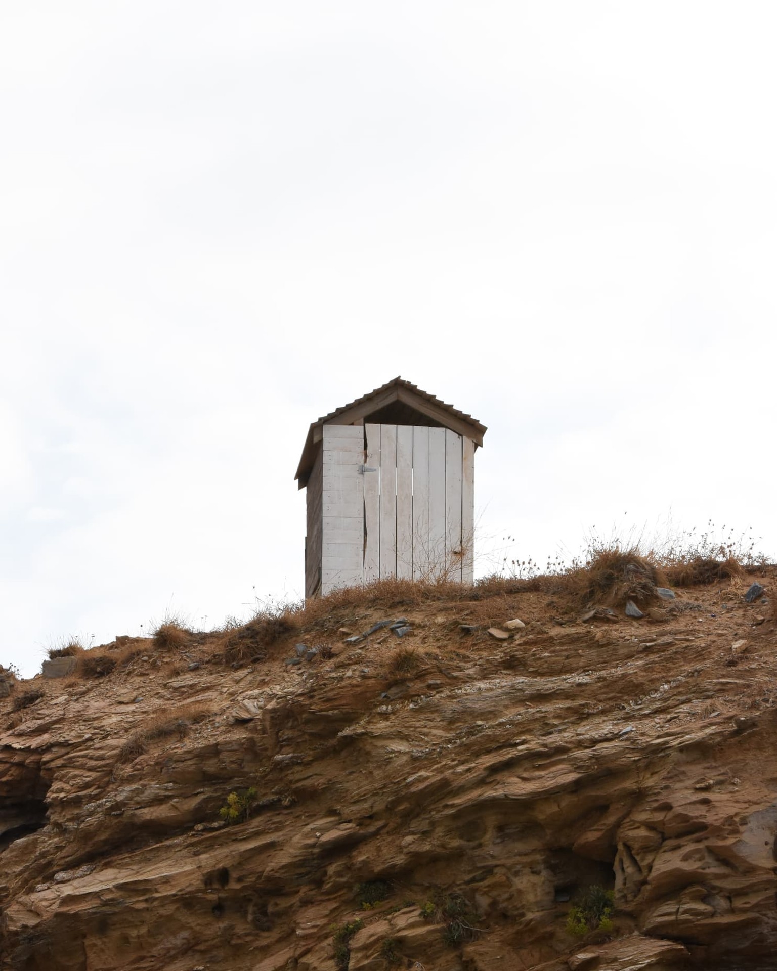 A weathered whitewashed shed on an arid headland