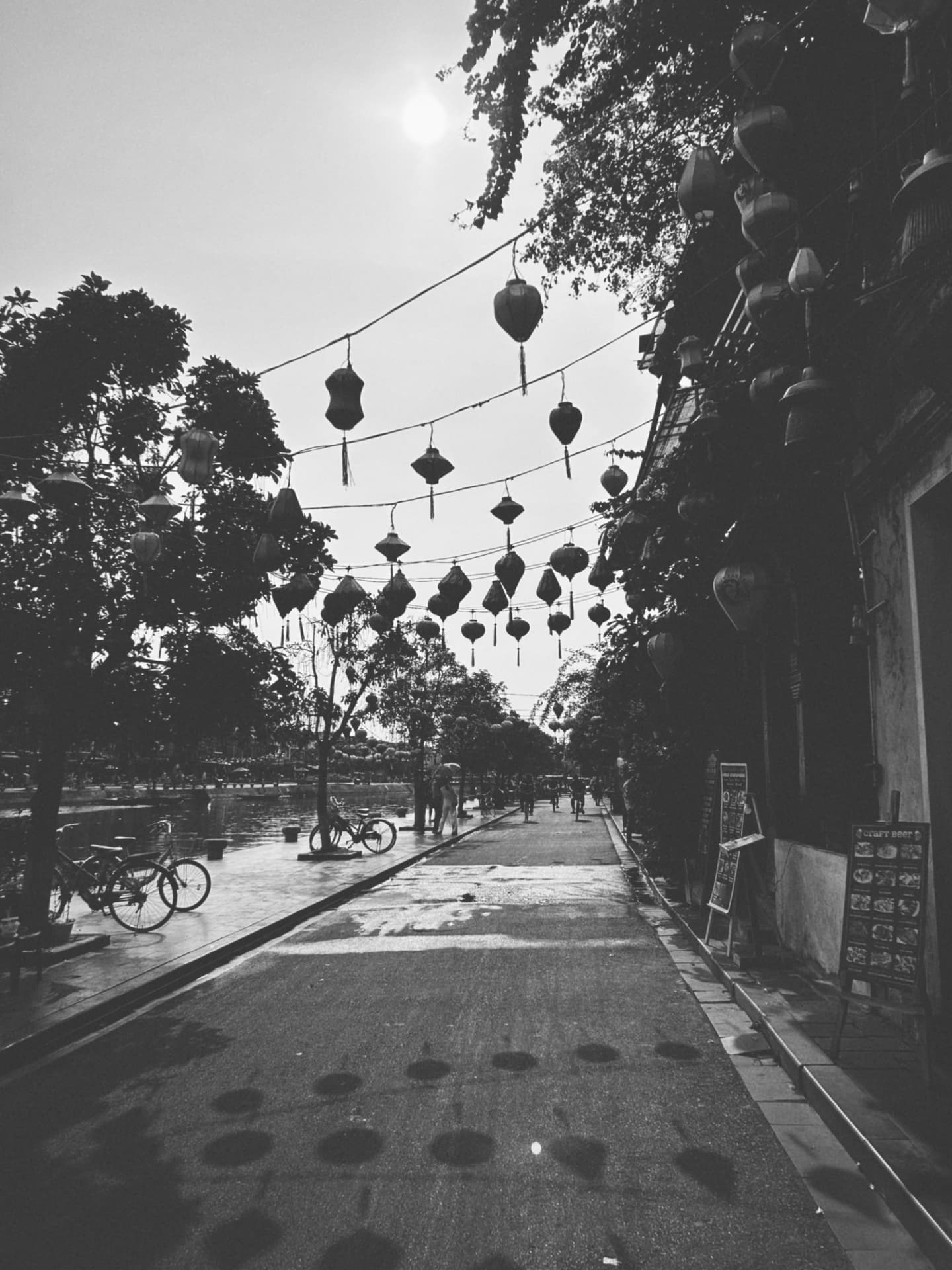 A riverside street hung with strings of paper lanterns