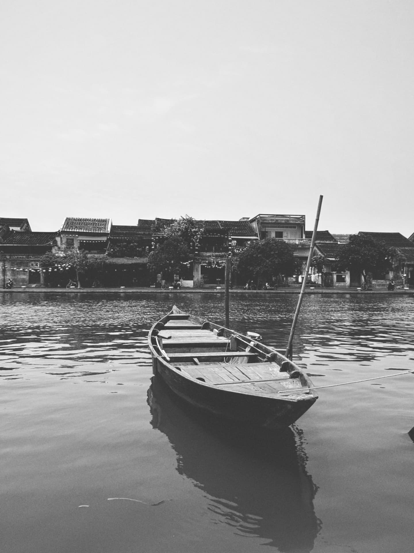 A moored wooden boat before an old waterfront of tiled houses