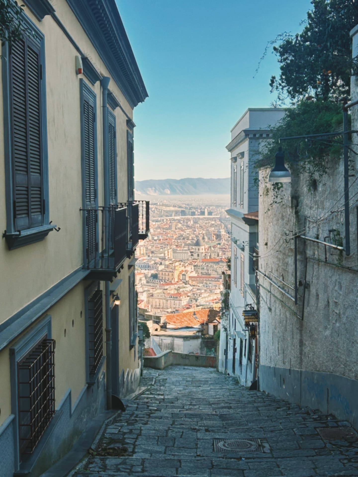 a steep cobbled street descending toward the city