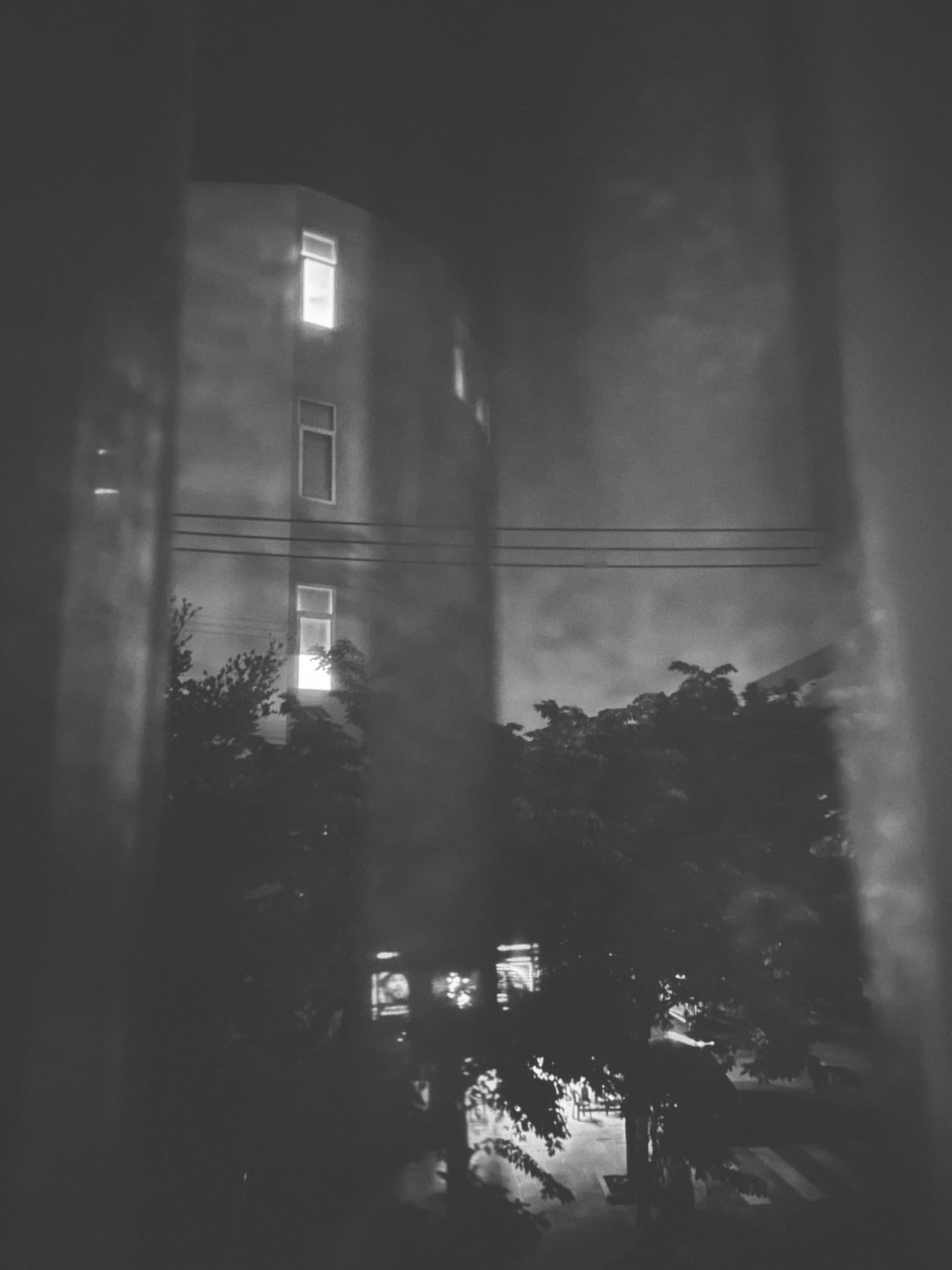 A wet street at night seen through a rain-speckled window