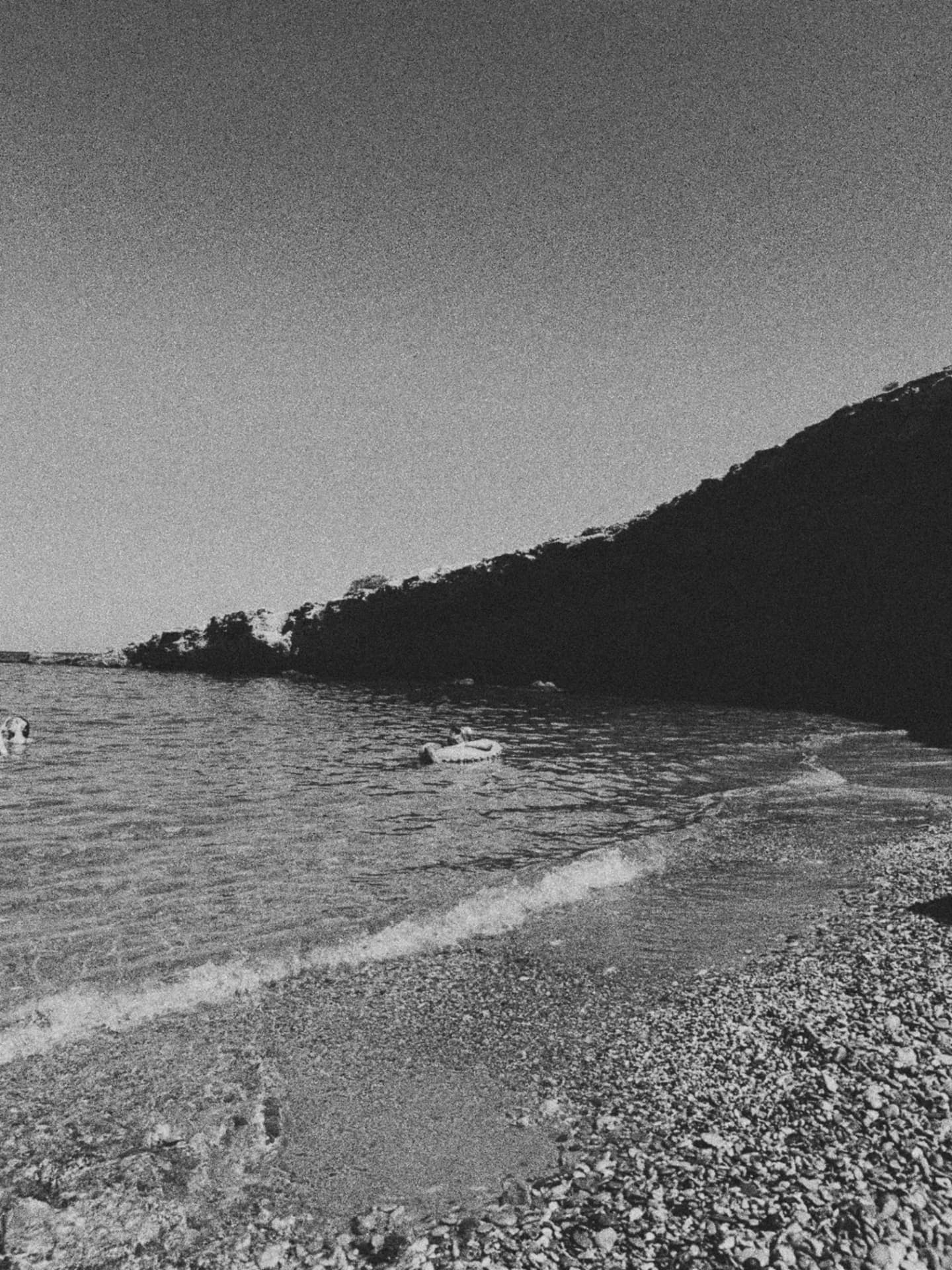 A pebble cove beneath a dark hillside