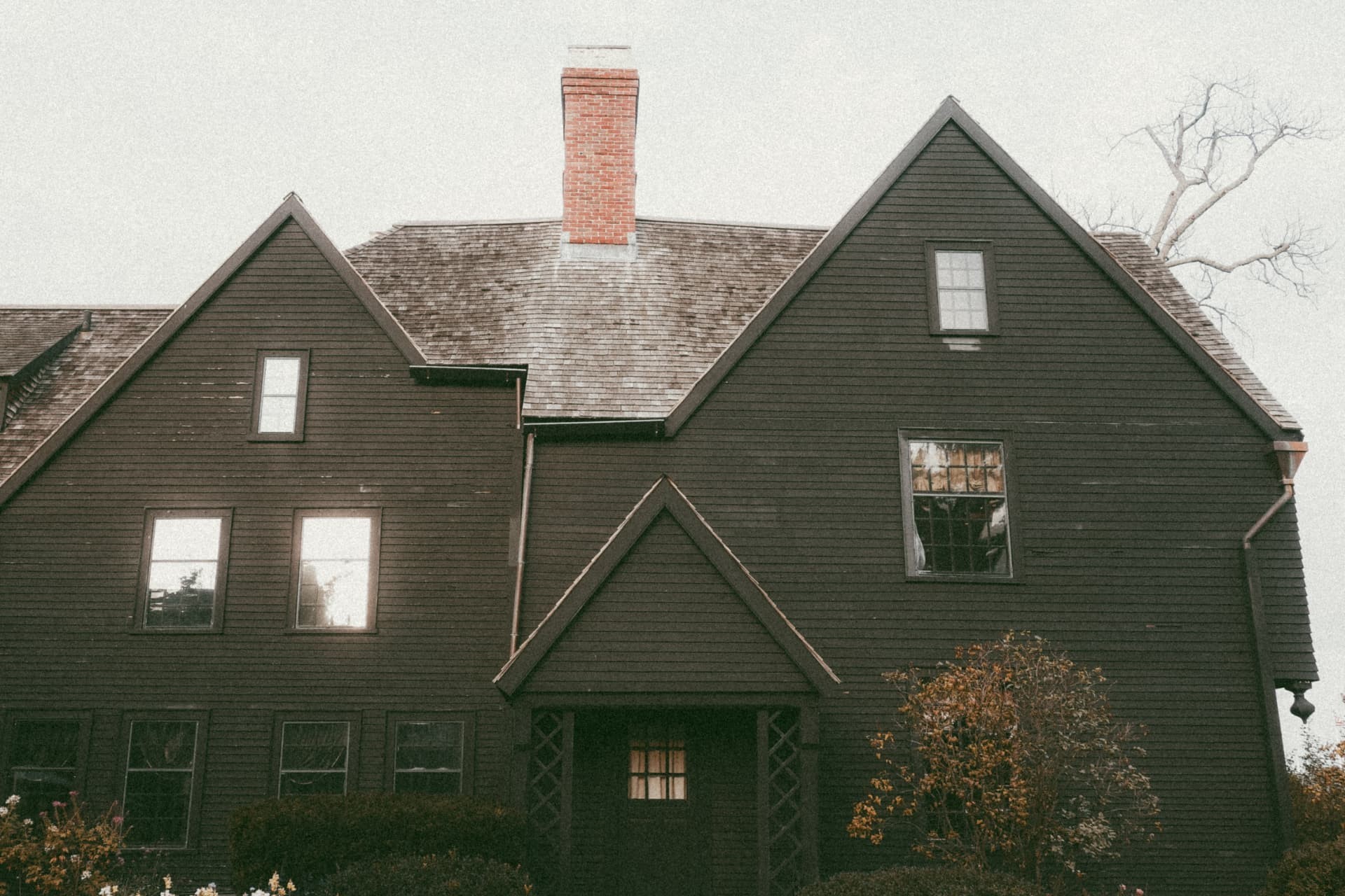 A dark timber house with steep gables and a brick chimney