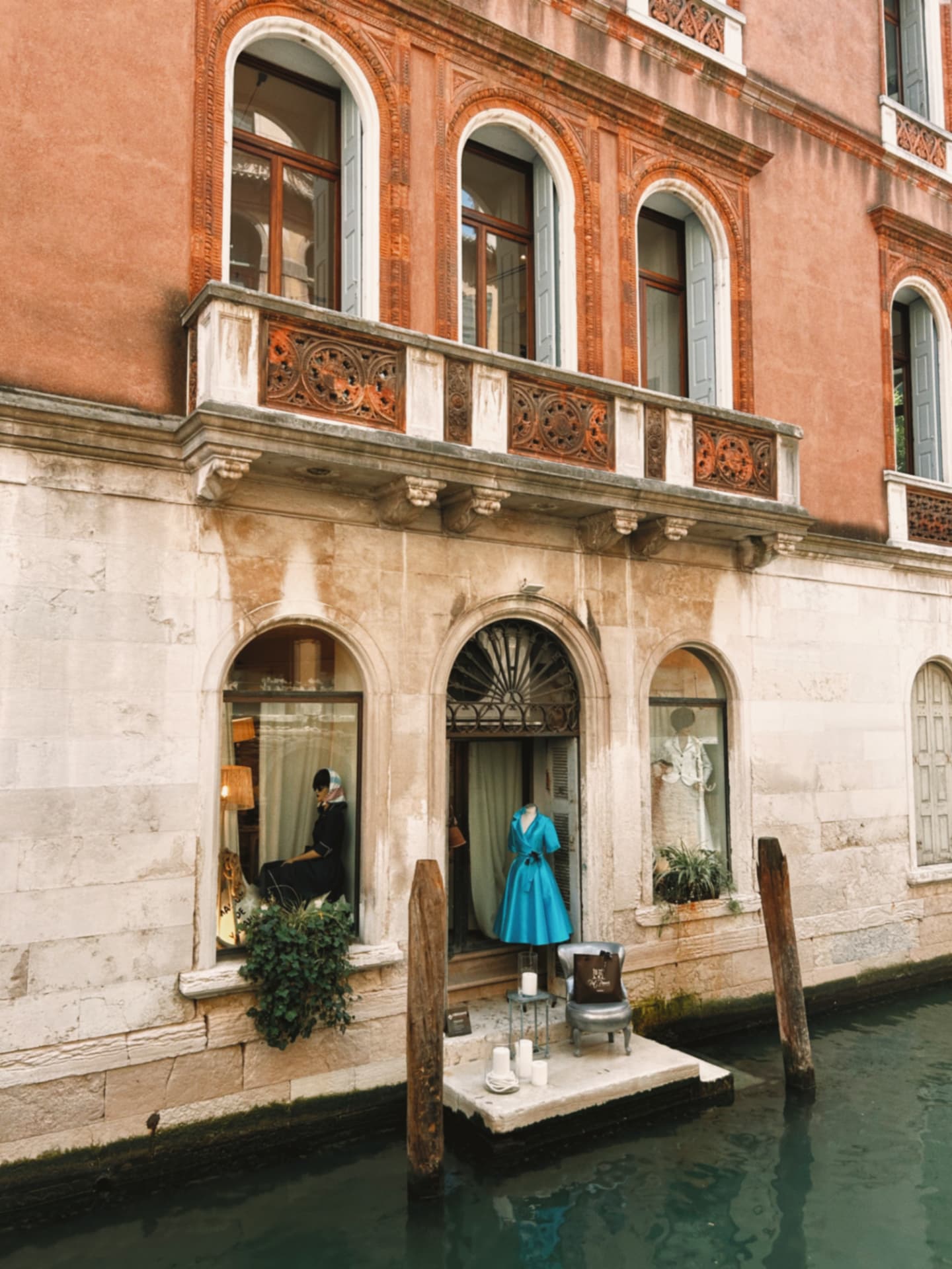 a canal-side boutique window with a turquoise dress