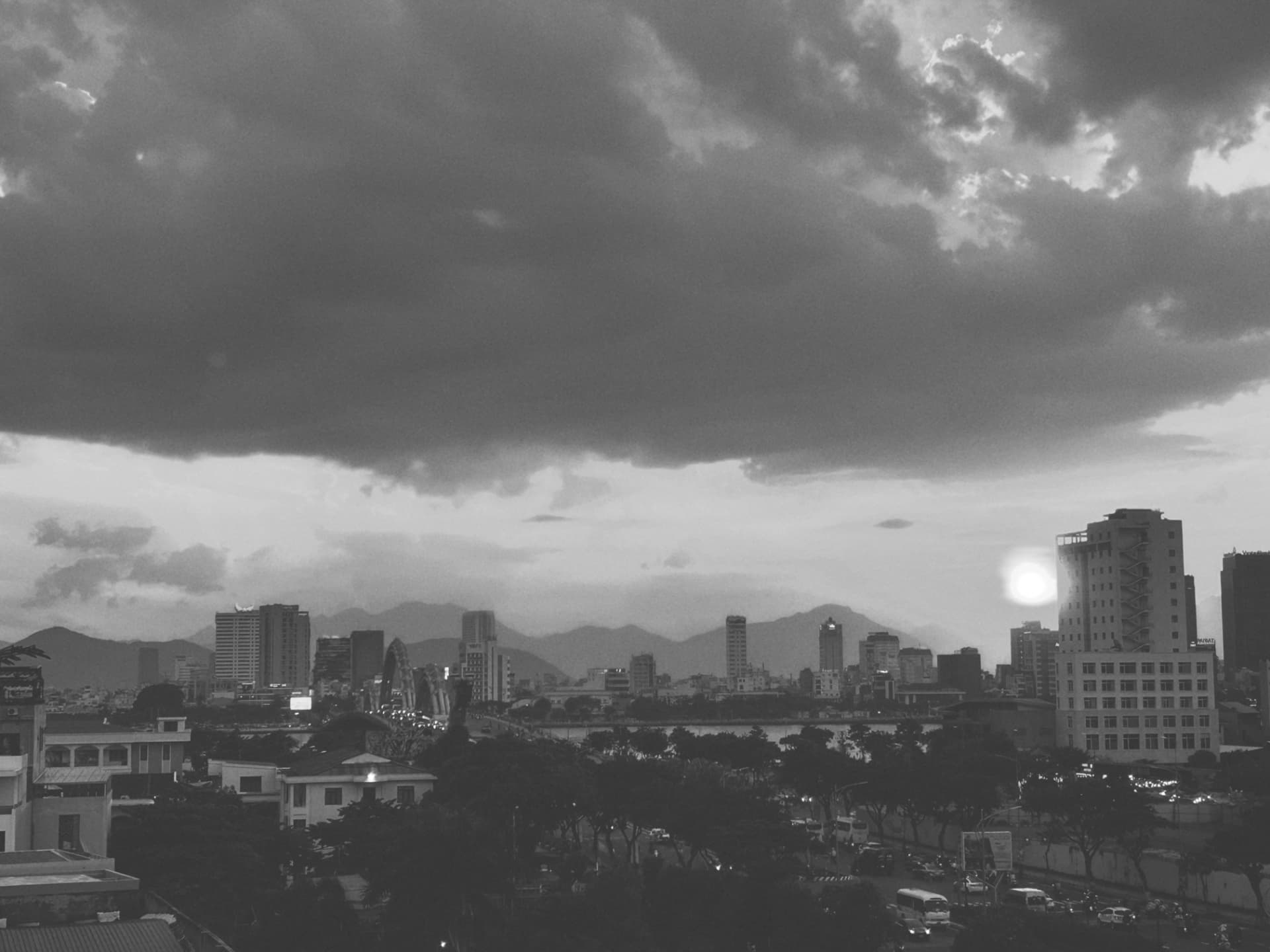 Heavy cloud over a city, its river and a bridge beyond