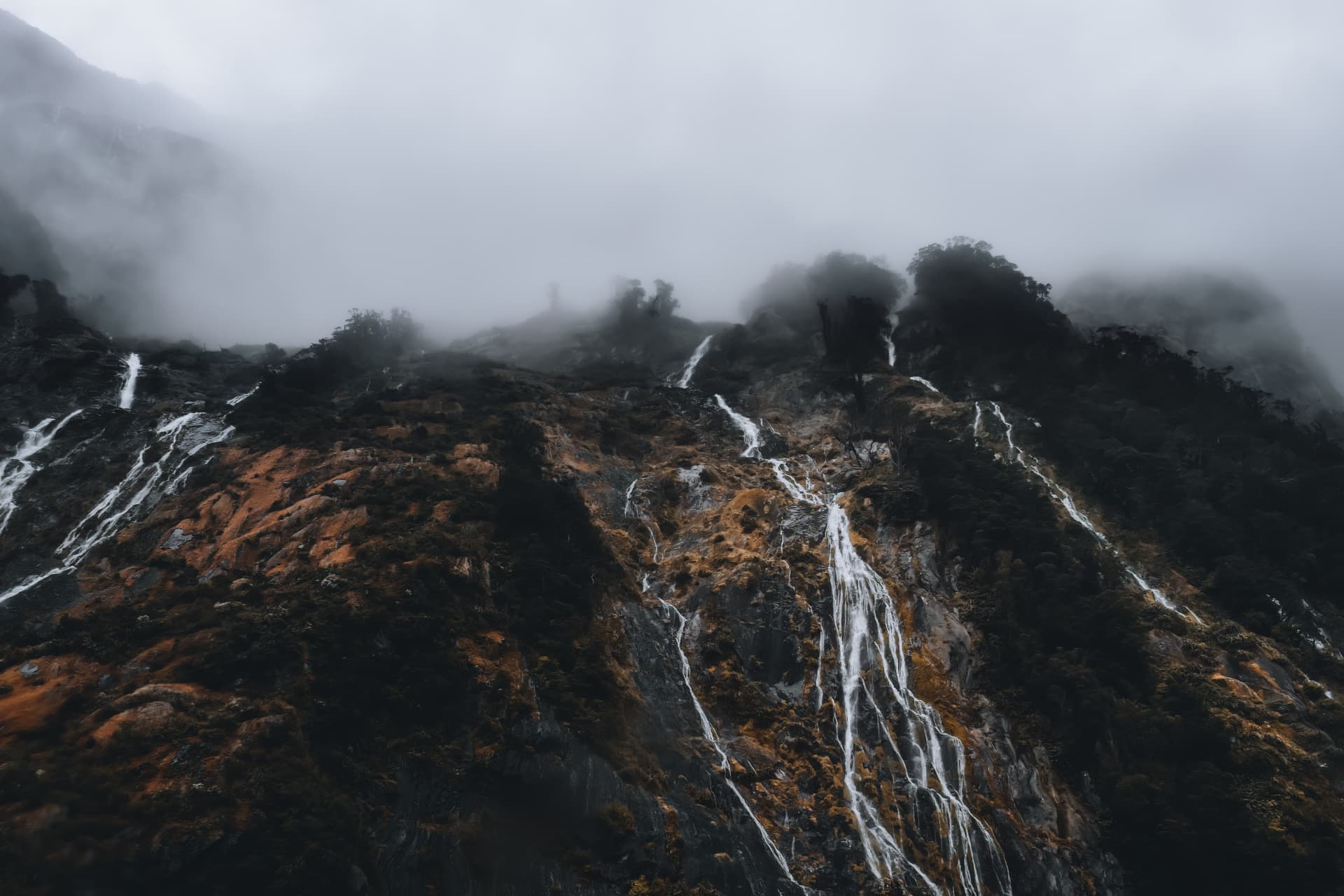Waterfalls streaking down a fog-shrouded mountainside