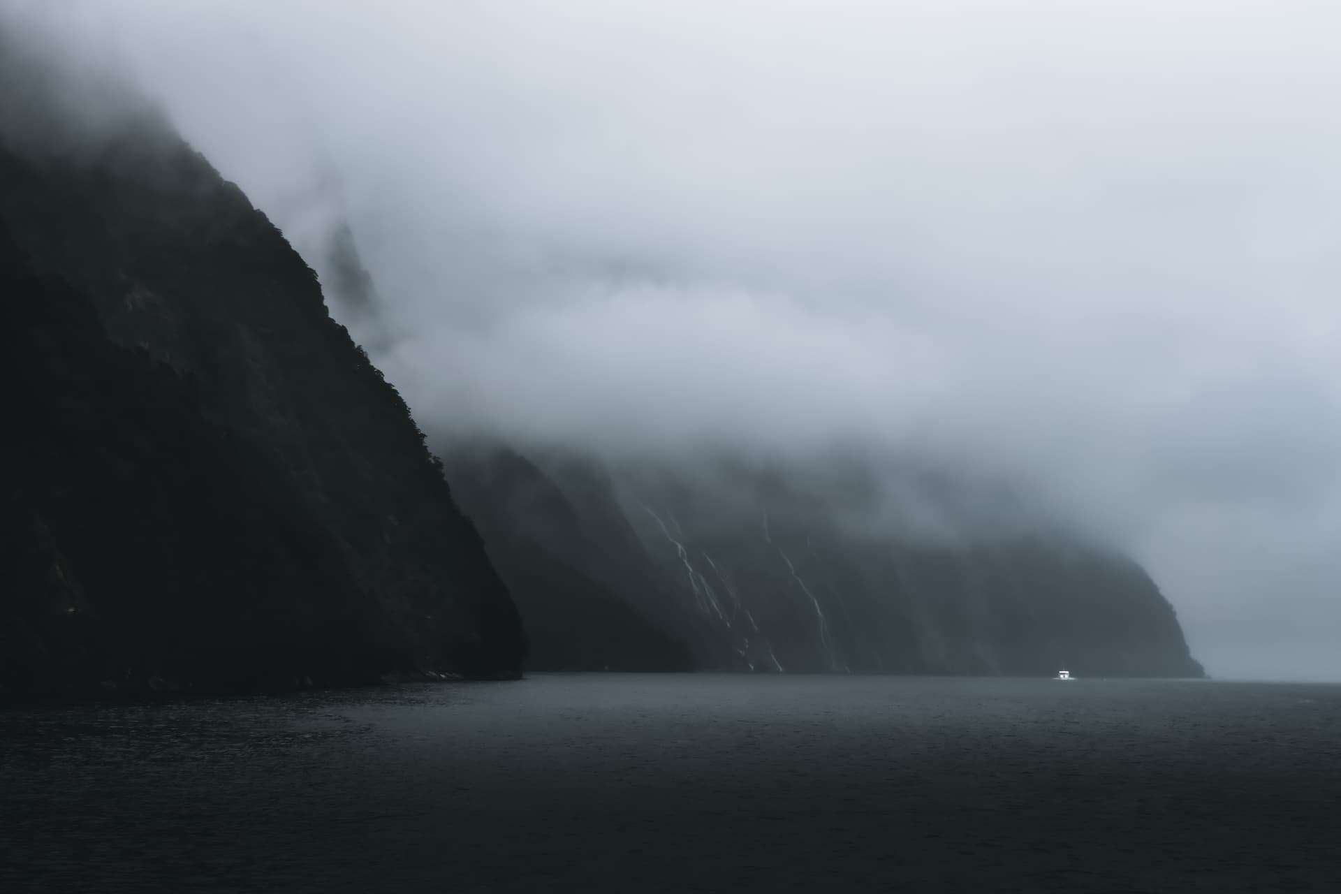 A misty fiord with sheer cliffs and a small boat