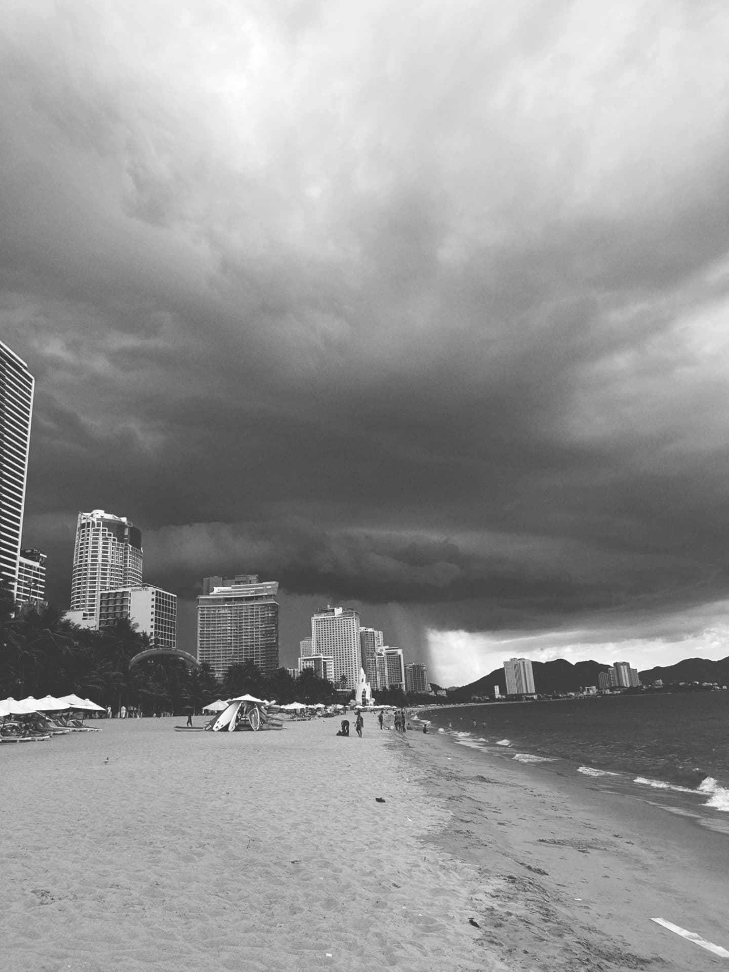 A dark storm cloud pressing over beachfront towers and parasols