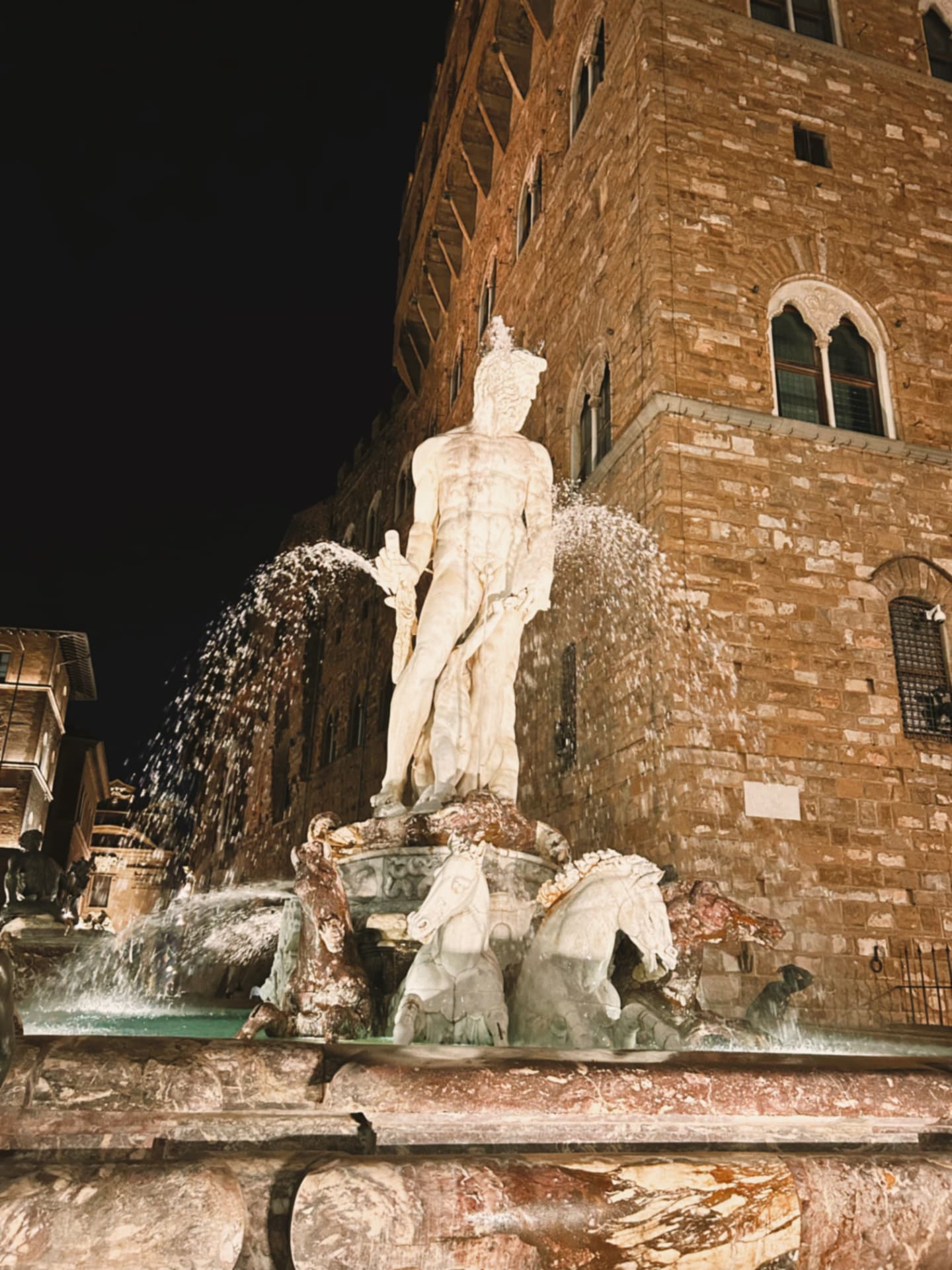 an illuminated fountain statue in a night piazza