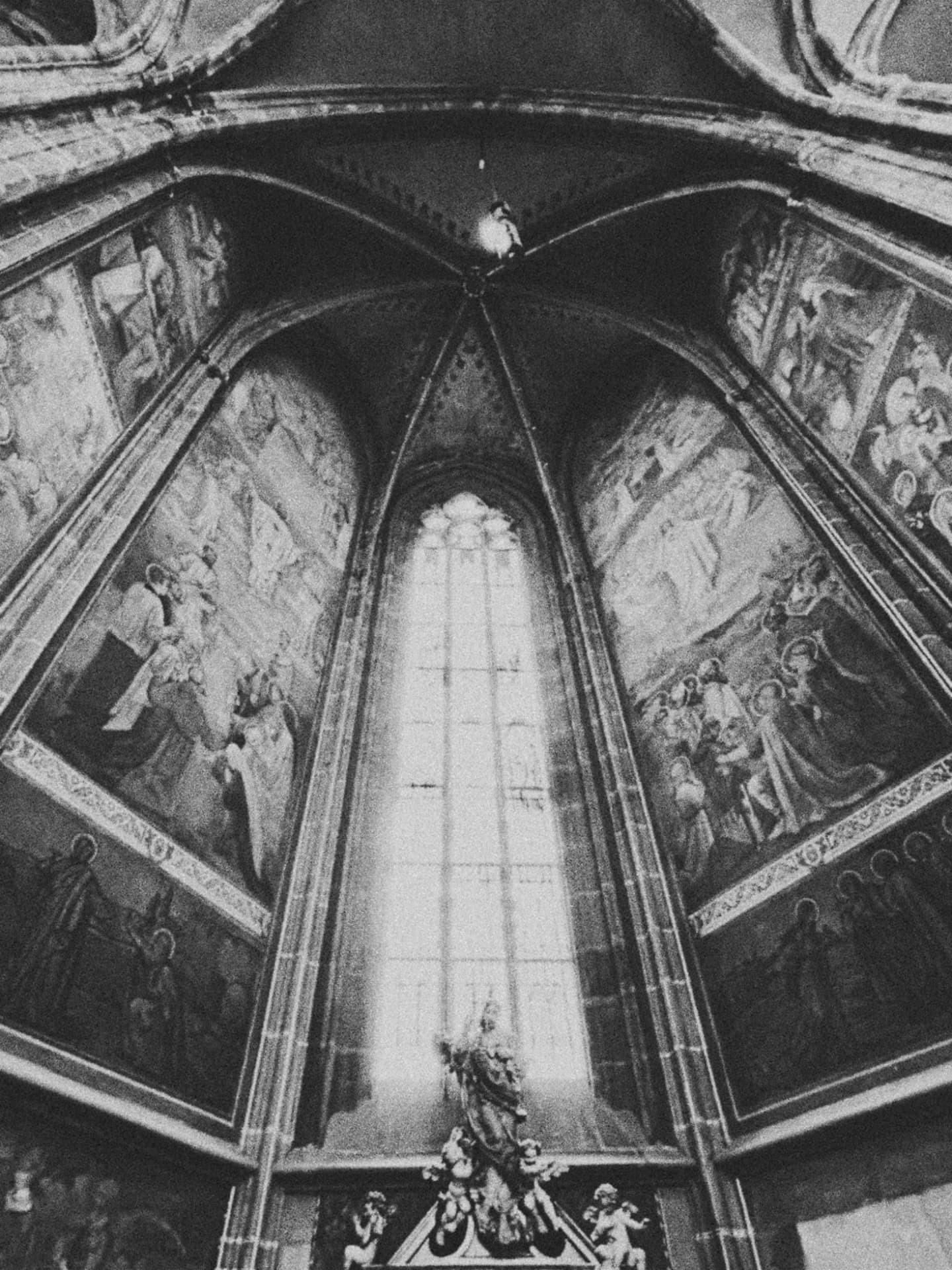 A painted apse rising above a tall arched window and altar figures