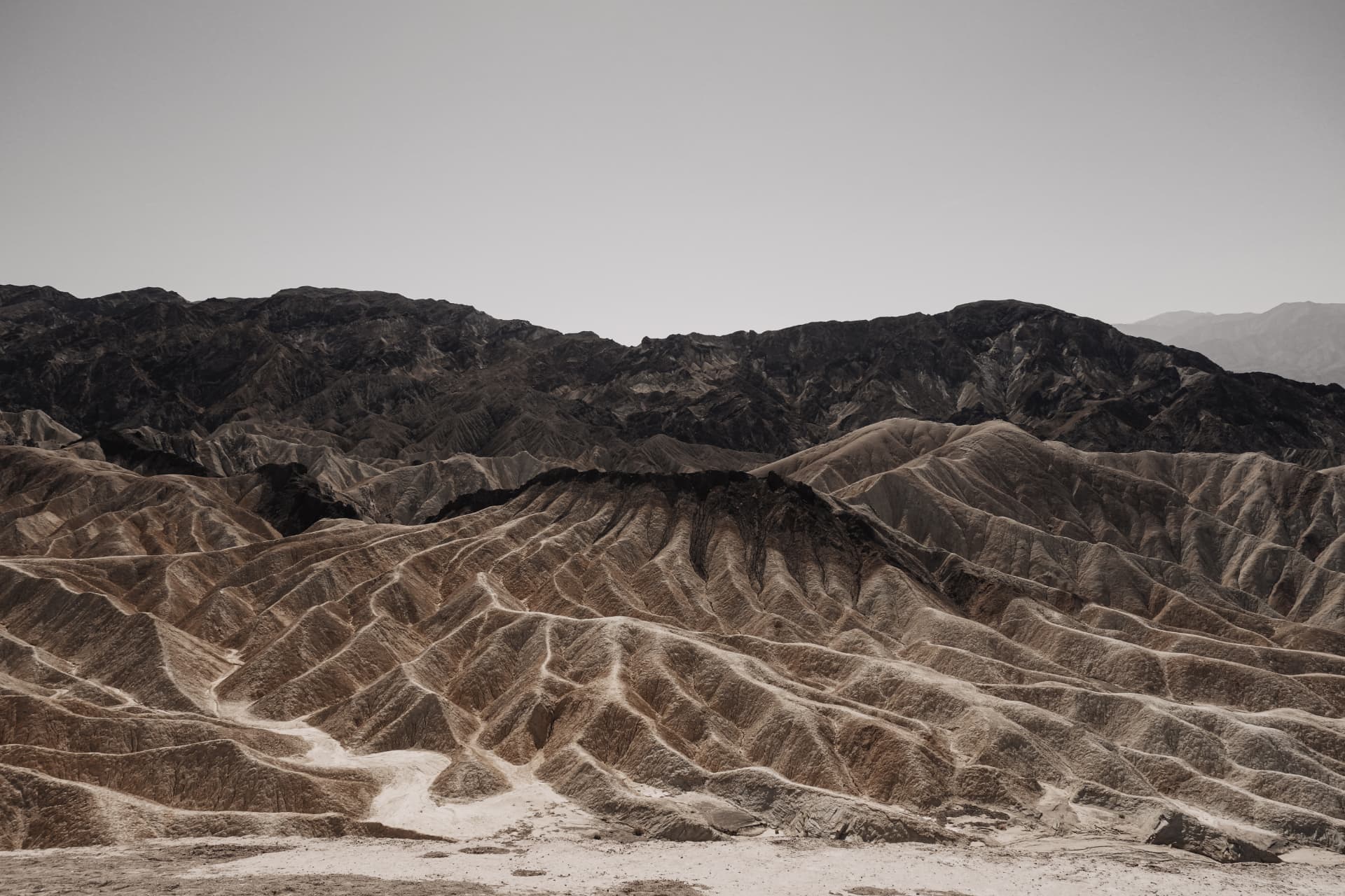 Eroded badland ridges above a pale salt flat