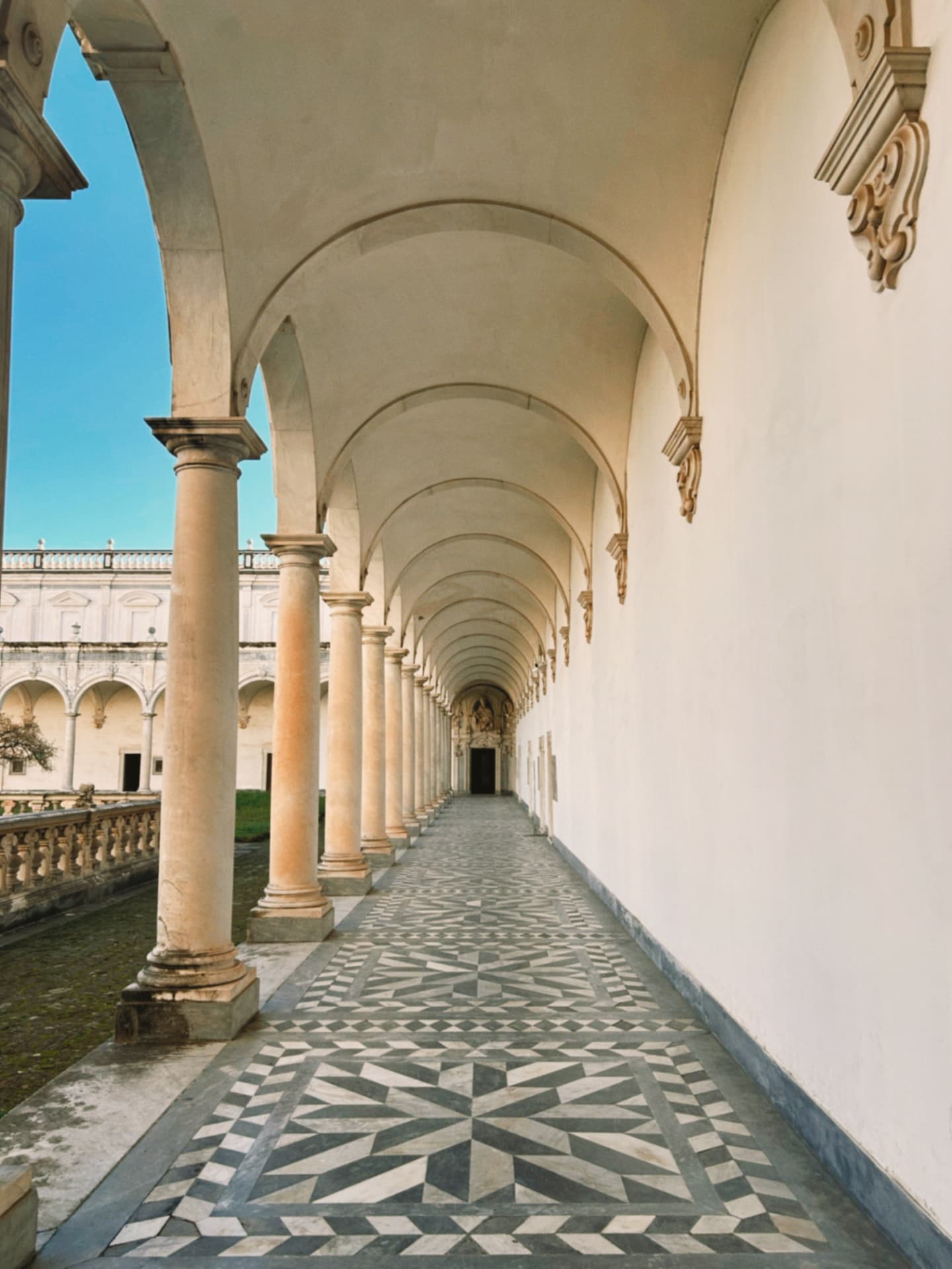 a white cloister corridor with a patterned floor