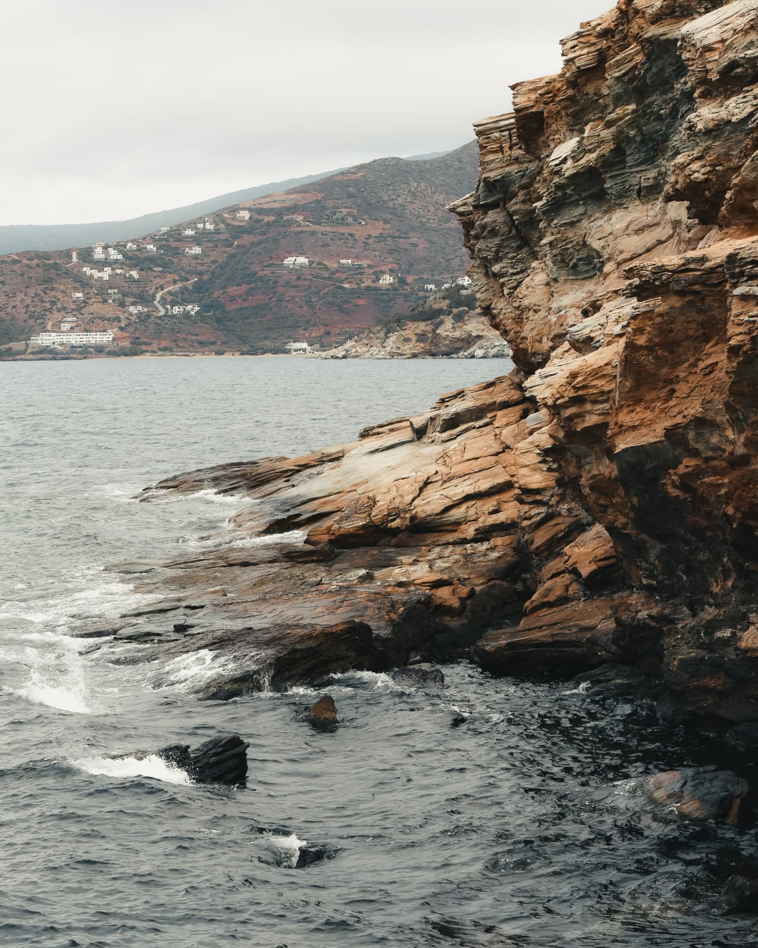 Layered coastal cliffs across a grey bay