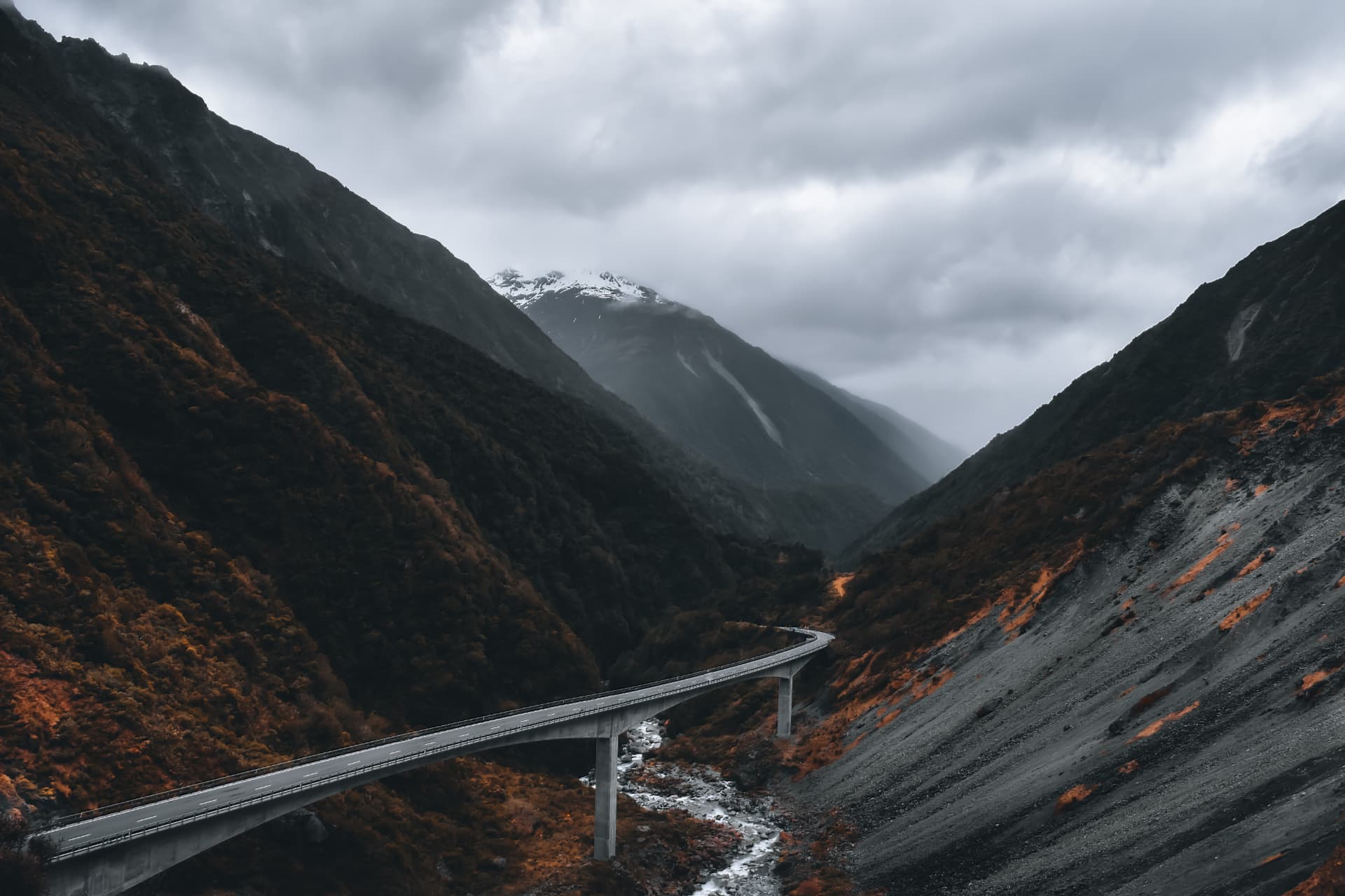 A road bridge crossing a glacial river in a misty valley
