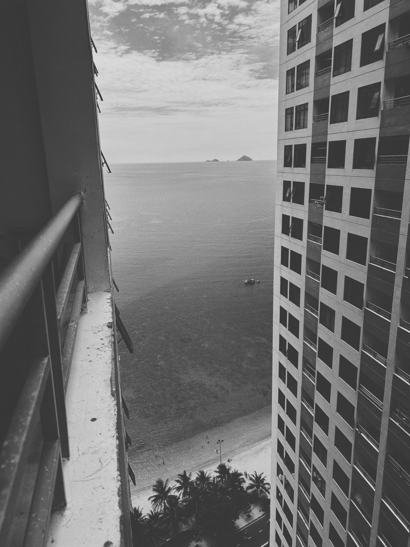 A balcony rail and tower wall framing the sea and beach below