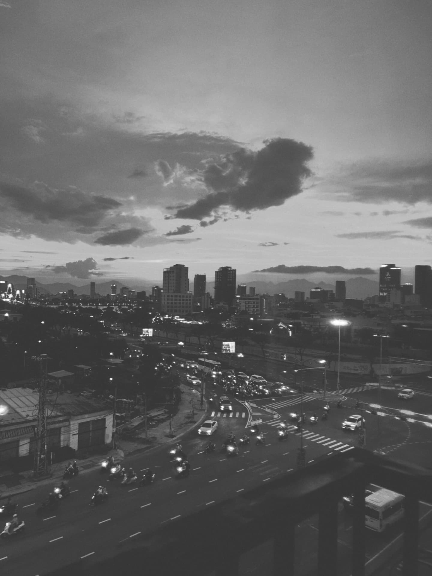 An evening boulevard of traffic beneath a wide clouded sky