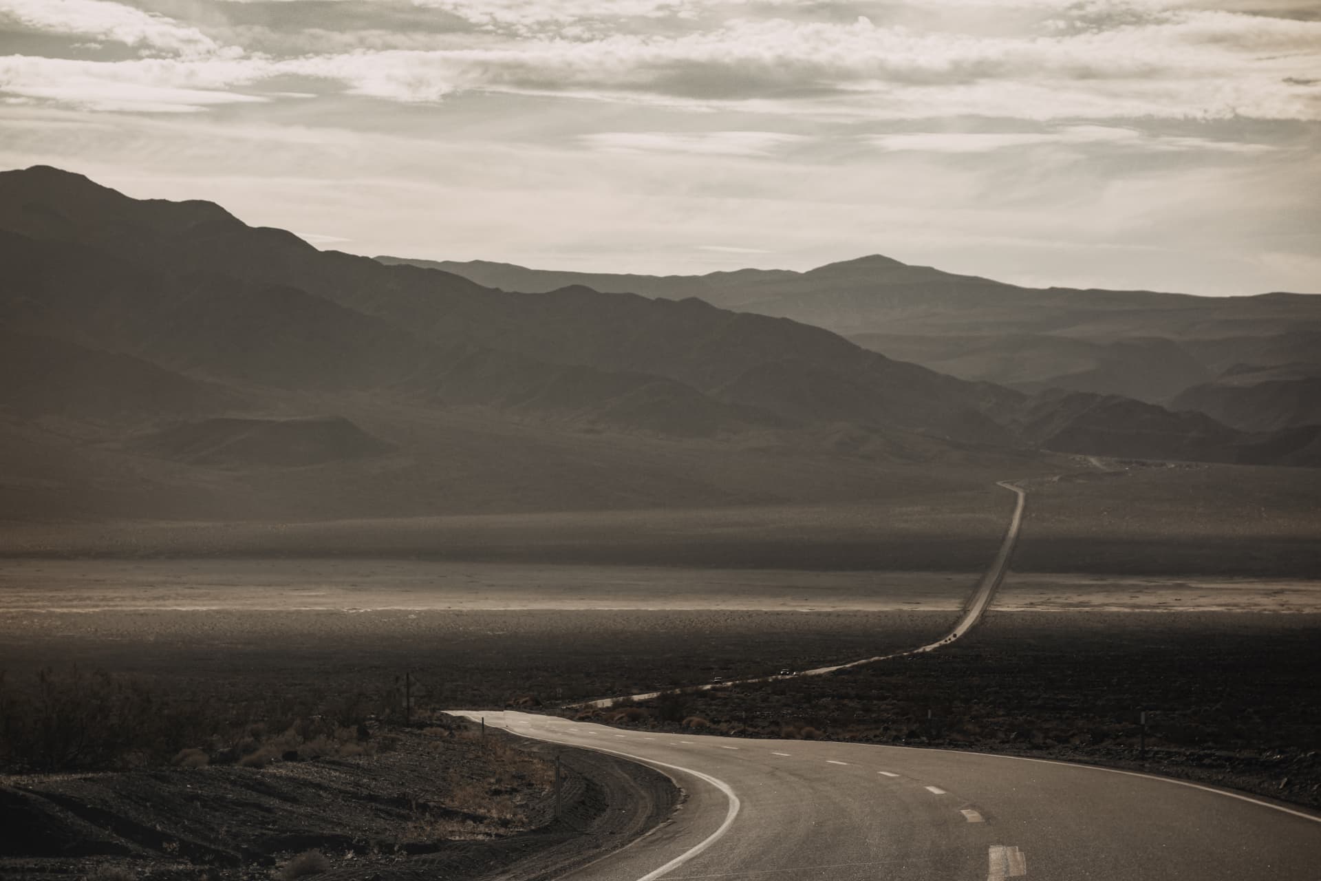 A winding road descending through a dark desert valley