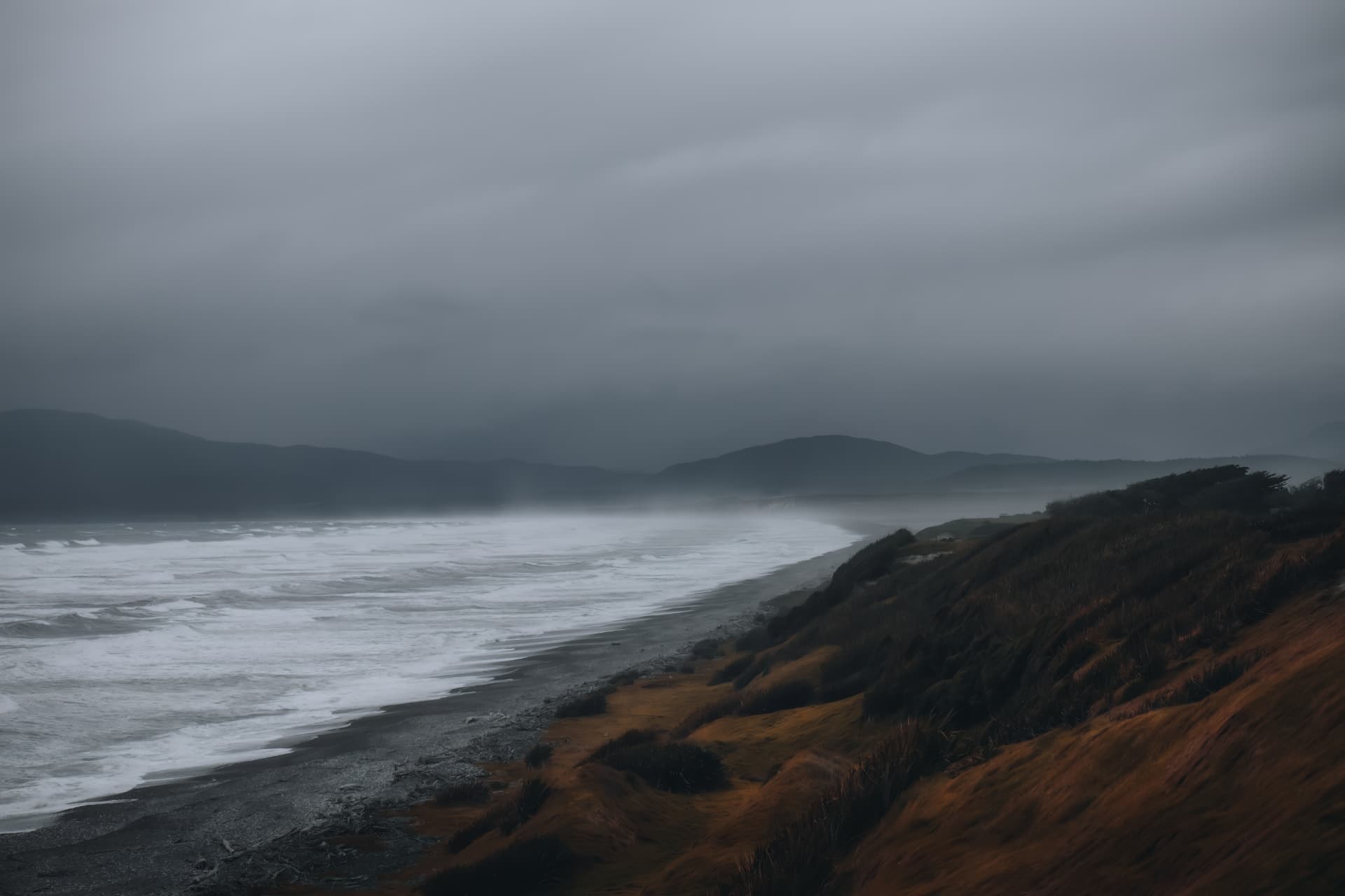 A stormy coastline curving past a grassy headland