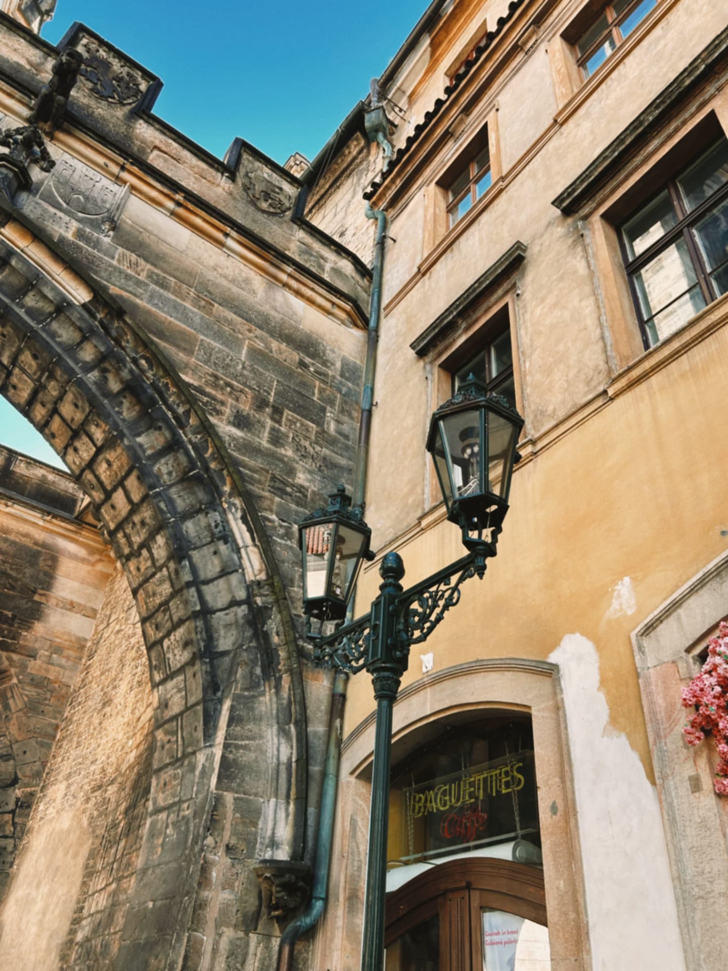 an ornate street lamp beside an old stone archway