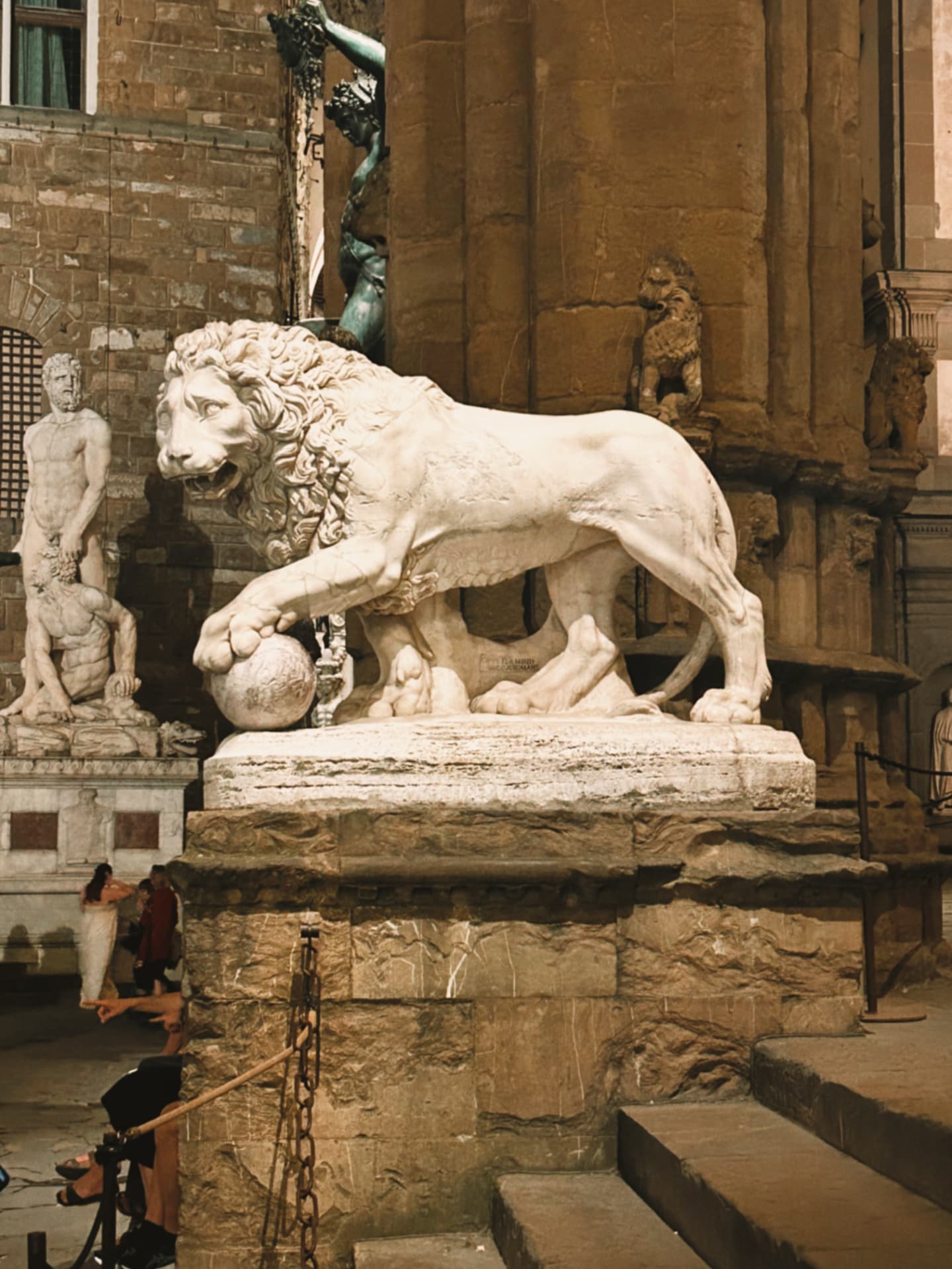 a pale marble lion among stone buildings