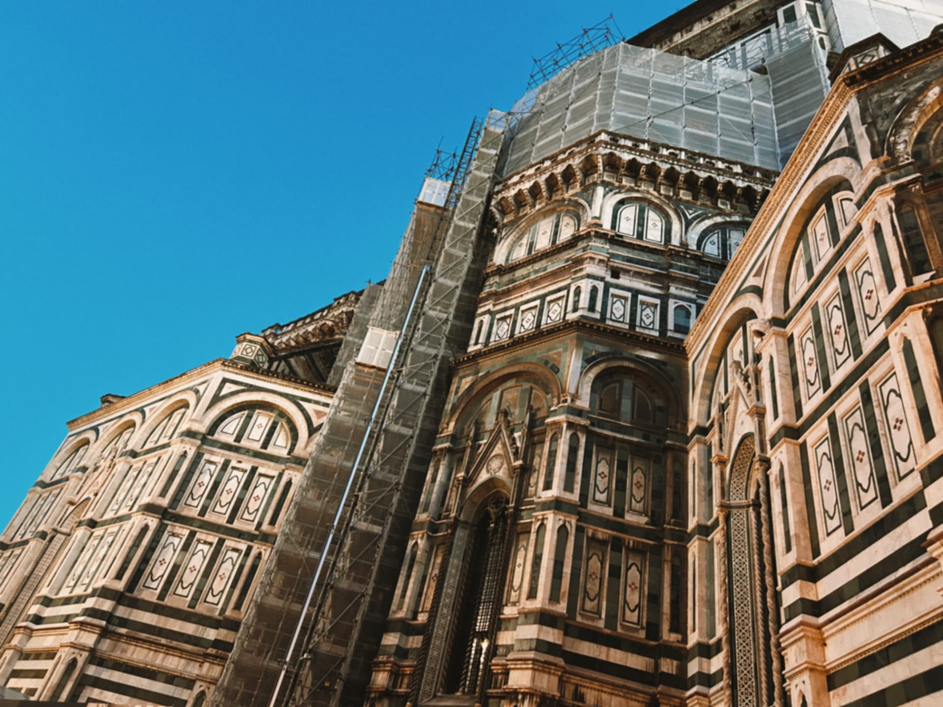 Florence cathedral's marble facade and scaffolding under a blue sky