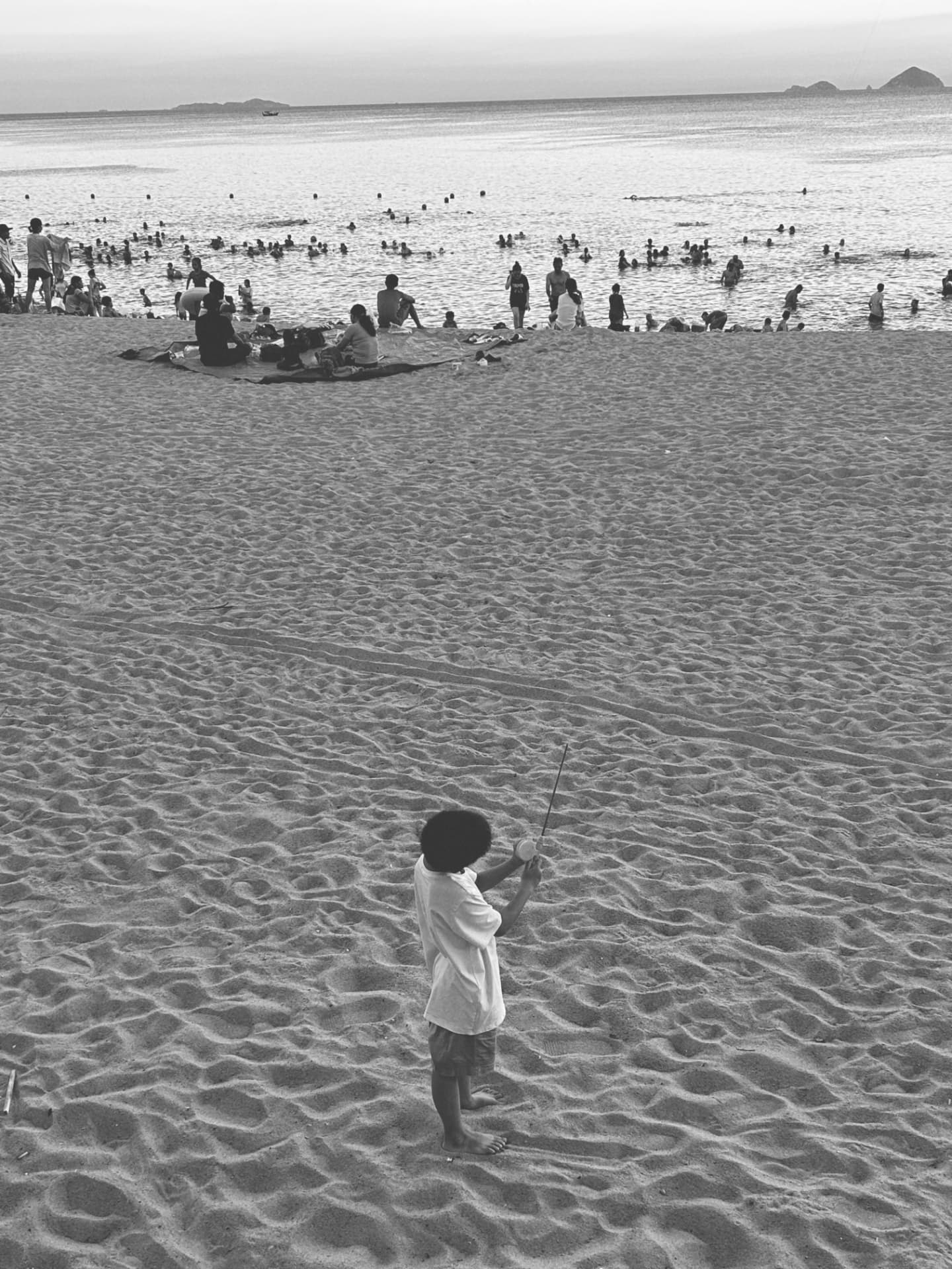 A child with a net standing alone on a wide sandy beach